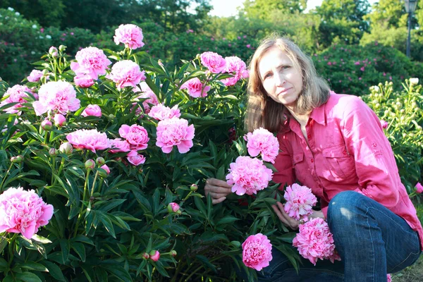 Femme près d'un buisson pivoines — Photo