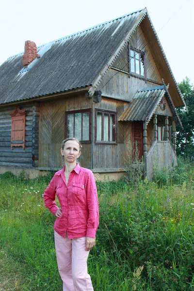 köyde bir ahşap evin yakınlarında bir kadın duruyor