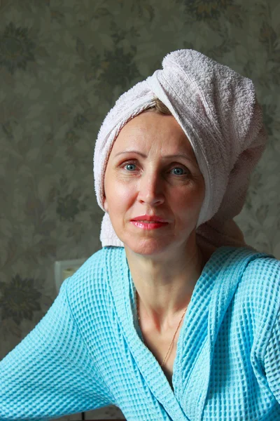 Uma mulher de roupão azul com toalha na cabeça — Fotografia de Stock