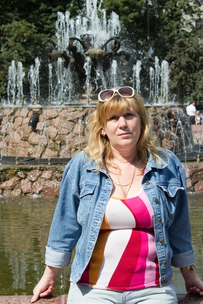 Eine Frau steht neben einem Brunnen — Stockfoto