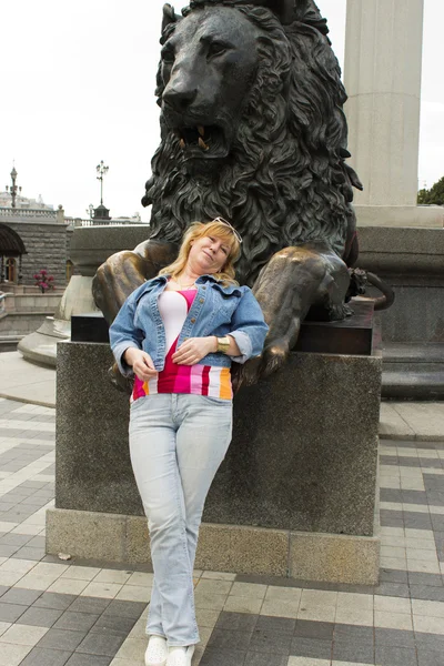 Une femme se tient près d'une sculpture d'un lion — Photo