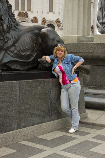 Una mujer está cerca de una escultura de un león —  Fotos de Stock
