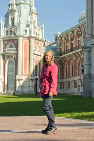 Una mujer con una chaqueta roja caminando cerca del palacio Tsaritsyno en th —  Fotos de Stock
