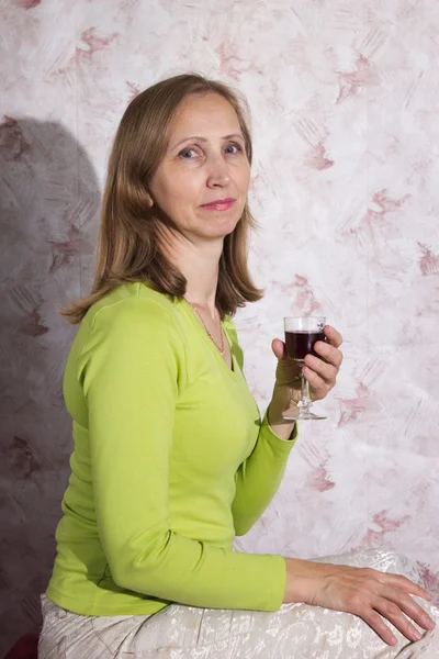 Una mujer en una blusa verde con una copa de vino —  Fotos de Stock