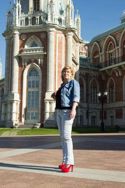 Una mujer con una chaqueta azul caminando cerca del palacio Tsaritsyno en t —  Fotos de Stock