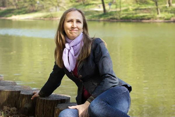 Woman sitting near a pond — Stock Photo, Image