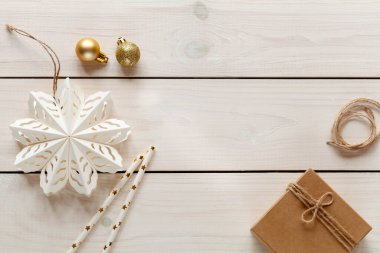 Beyaz ahşap arka plan, kar tanesi, el işi hediyesi ve altın dekor.