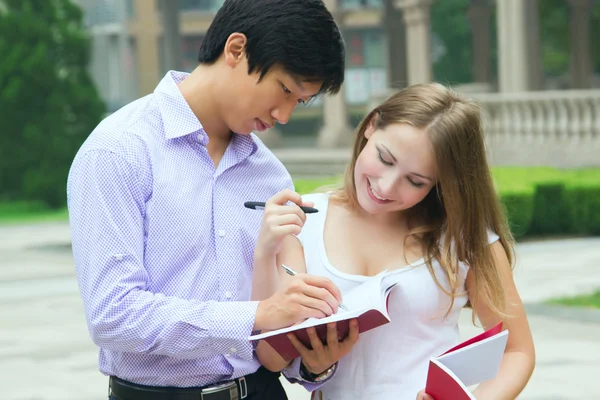 Male school teacher write and explain something to female studen — Stock Photo, Image