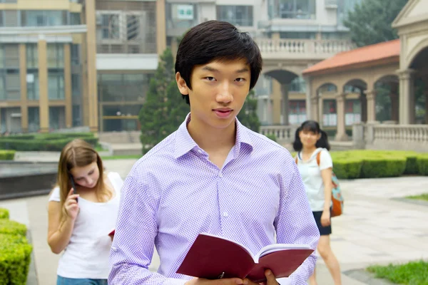 책을 들고 웃 고 젊은 아시아 남자 학생의 초상화 스톡 사진
