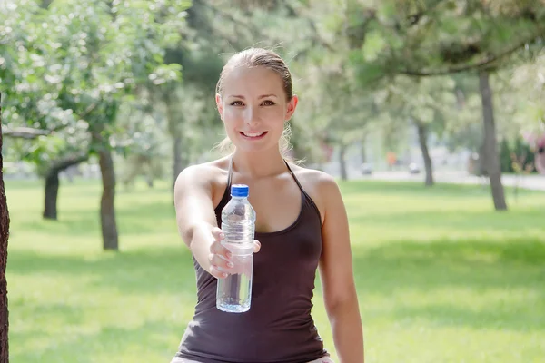 Жінка тримає пляшку холодної води в зеленому парку Стокове Зображення
