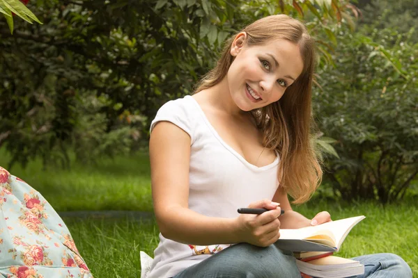 Unga ganska kvinnlig student med böcker som arbetar i en park — Stockfoto