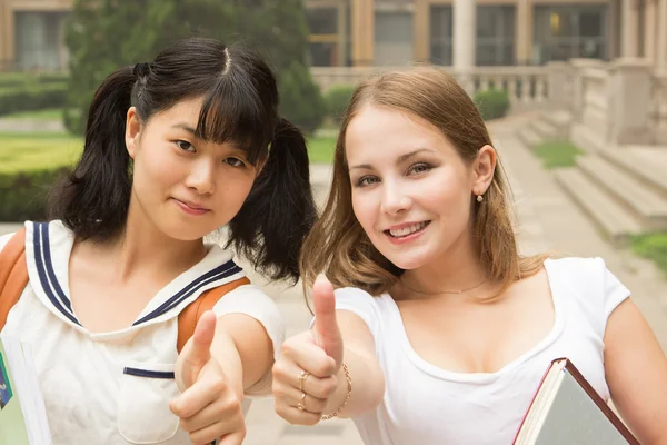 Estudantes no parque sorrindo e mostrando polegares para cima sinal de sucesso — Fotografia de Stock