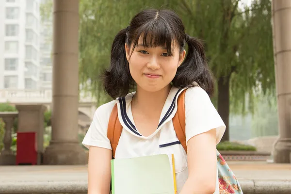 Gülümseyen kız Asya öğrenci kitaplarını taşıyor Stok Fotoğraf