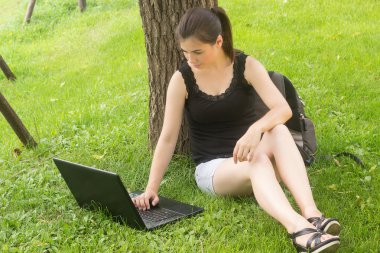 liseli kız öğrenci parkta dizüstü ev ödevi yapmak