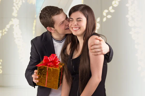 Молодий чоловік обіймає свою дівчину і пропонує подарунок — стокове фото