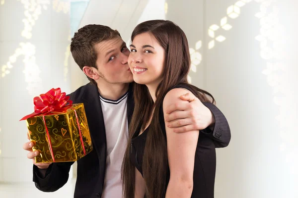 Άνθρωπος κρατώντας δώρο για τη γυναίκα και φιλάει Εικόνα Αρχείου