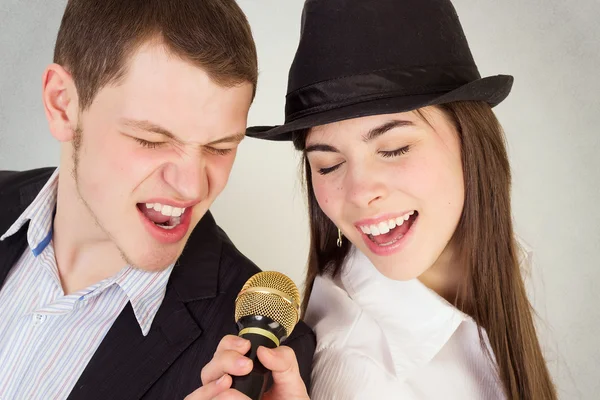 Mann und Frau singen am Mikrofon Stockbild