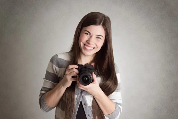 Mujer joven sonriente sosteniendo una cámara en las manos — Foto de Stock