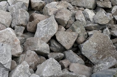 Bir istinat duvarı için kullanılan gri taşlar yığını.