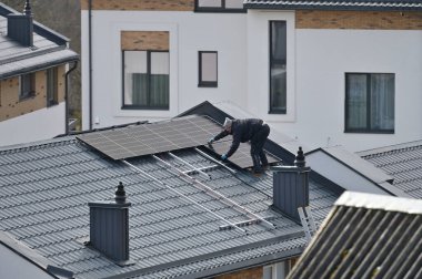 Vilnius, Litvanya - Nisan 06, 2022: Vilnius, Litvanya 'da çatıya güneş panelleri kuran adam.