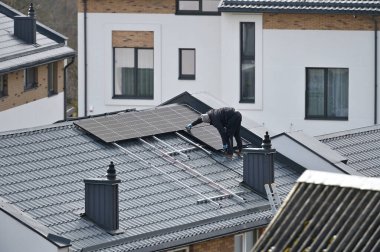 Vilnius, Litvanya - Nisan 06, 2022: Vilnius, Litvanya 'da çatıya güneş panelleri kuran adam.