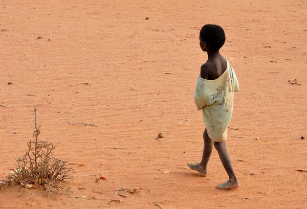 Poor boy walking barefoot on the sandl. Poverty concept — Stock Photo, Image