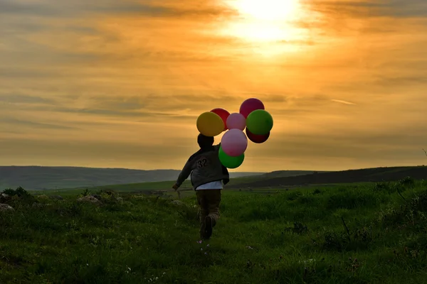 Palloncino nelle mani dei bambini che corrono verso il sole — Foto Stock