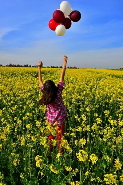 Jovem menina soprando bolha em um campo de flores amarelas — Fotografia de Stock