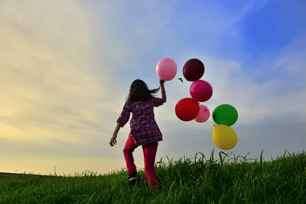 Ballon a kezében egy fiatal lány futás-ban a réten — Stock Fotó