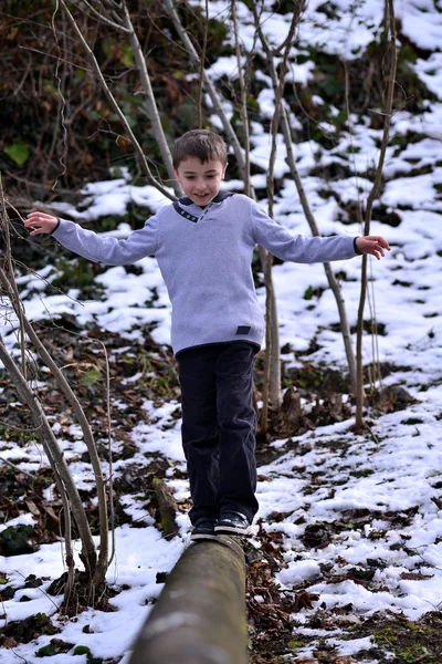 Хлопчик балансує на колоді взимку — стокове фото