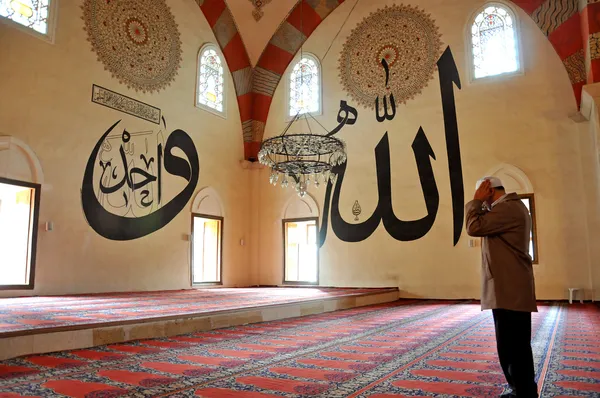 Människor ber i moskén och arabiska skrifter — Stockfoto