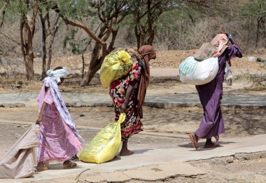 Afrikalı kadınlar yardım taşıyan evlerine aldıkları