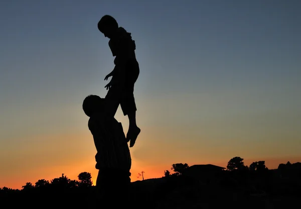 Papai joga a criança ao pôr do sol — Fotografia de Stock