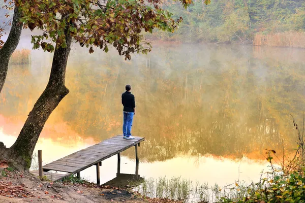 Autumn landscape reflected in the water facing the young — Stock Photo, Image