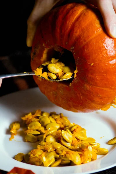 Férfi Kezek Kanállal Kaparják Magokat Egy Őszi Tökből Halloweenkor Konyhaasztalon — Stock Fotó