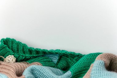 Beyaz bir duvar zemininde beyaz bir rattan topuyla desenli, çok renkli örgü süveter. Yatay format. Hobi, zanaat, el yapımı..