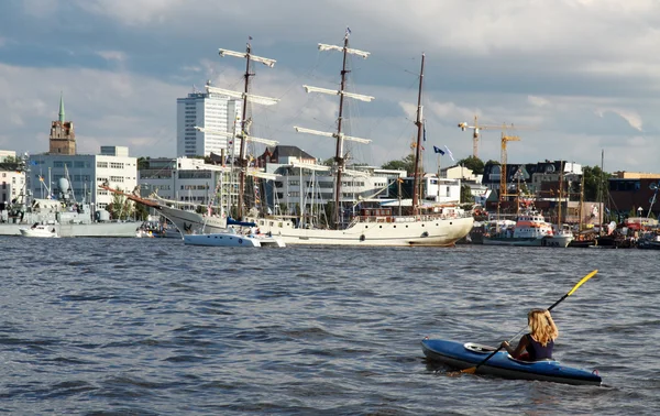 Young women join the sailing ship parade with her kayak — Stock Fotó