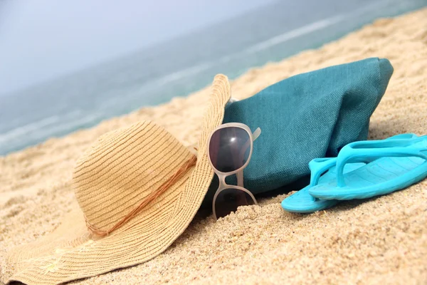 Blauwe strandtas op de zeekust en stro hoed — Stockfoto