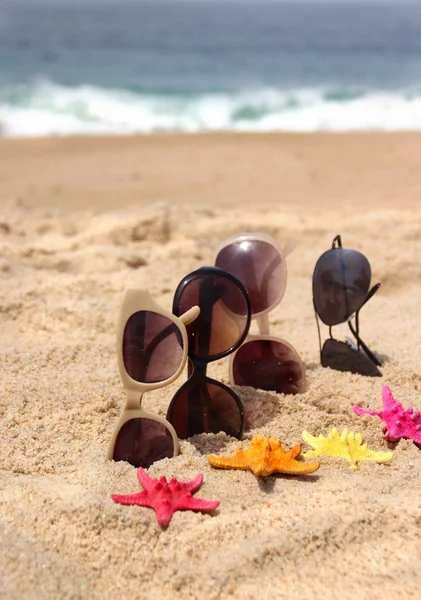 Four pairs of sunglasses on the beach — Stock Photo, Image