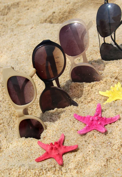 Four pairs of sunglasses on the beach — Stock Photo, Image