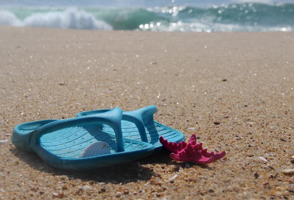 Slippers en roze zeester op het strand — Stockfoto
