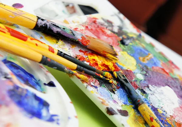 Art palette and paintbrushes — Stockfoto