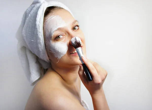 Mladá krásná žena s jíl obličeje masku na tváři — Stock fotografie