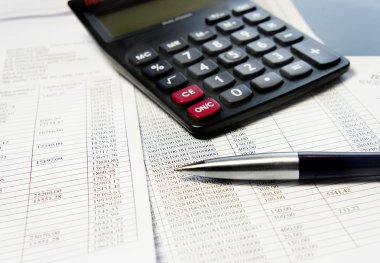 hesap makinesi, kalem ve muhasebe belgesi ile ofis masaları