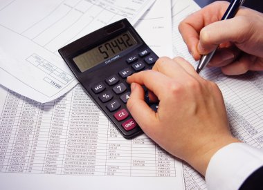 hesap makinesi, kalem ve muhasebe belgesi ile ofis masaları