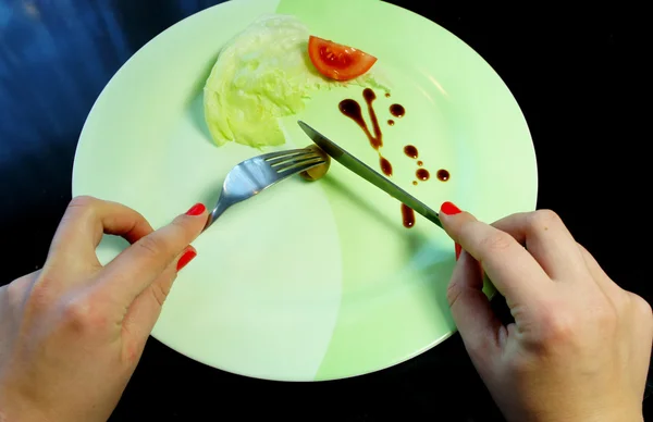 Big plate with a little piece of food and woman hands — Stock Photo, Image