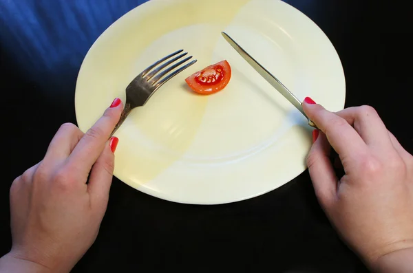 Big plate with a little piece of food and woman hands — Stock Photo, Image