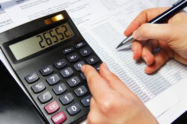 hesap makinesi, kalem ve muhasebe belgesi ile ofis masaları