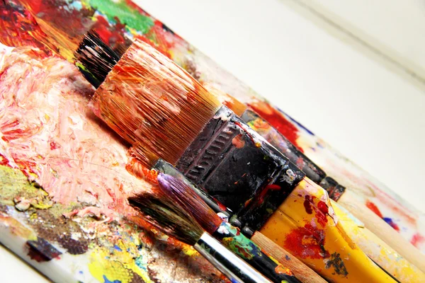 Beautiful vivid art palette and mix of paintbrushes — Stock fotografie