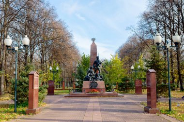 1812 Vatansever Savaşı Kahramanları Anıt Park Kompleksi. Rus ordusundan bir piyade, yaralı bir savaşçı ve onu destekleyen bir yoldaştan oluşan bir takım elbise giymiş uzun boylu bir asker. Arkalarında kırmızı granitten bir dikilitaş var. 